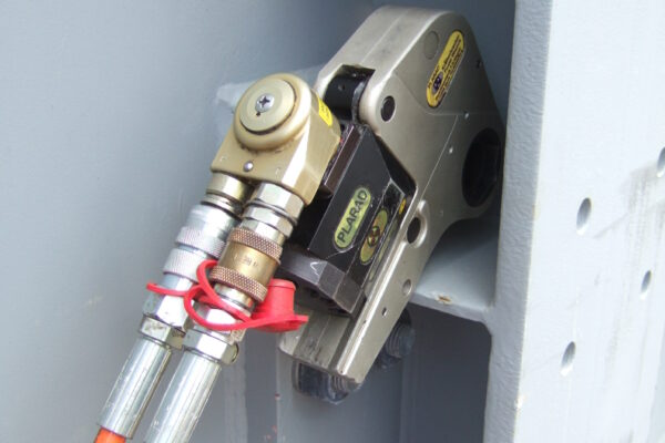DSCF7039 A hydraulic torque wrench is expertly attached to a metal structure and fitted with orange cables, demonstrating the efficiency of Plarad's structural steel industry solution.