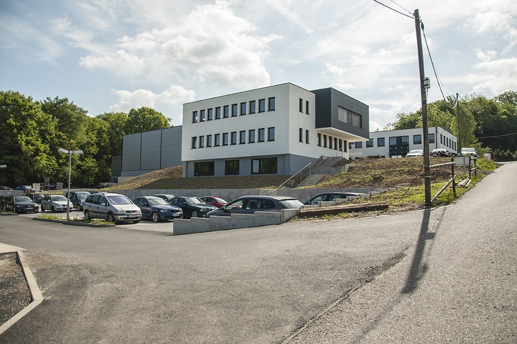 Zu sehen ist das Firmengebäude von Plarad mit Parkplatz.