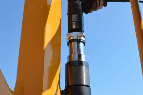 Close-up of a person using a DE2 electric nutrunner on a large yellow metal structure against a clear blue sky, embodying Plarad's innovative construction machinery and crane industry solution.