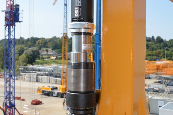 A worker is fastening a bolt with a electric nutrunner to a yellow steel structure on a construction site, demonstrating the precision and efficiency typical of Plarad's construction machinery and crane industry solution.