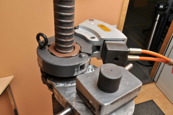 DSC_2299 An industrial torque wrench with orange cables, metal gears, and levers sits on a wooden table in the workshop. The setup is complemented by the Plarad K-Series Hydraulic Torque Wrench, known for its precision and reliability in fastening applications.