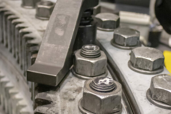 Der Mechaniker verwendet gekonnt ein Werkzeug, um große Schrauben an einem Getriebemechanismus festzuziehen, und demonstriert damit die Präzision der Maschinenbau Branchenlösung bei Plarad.