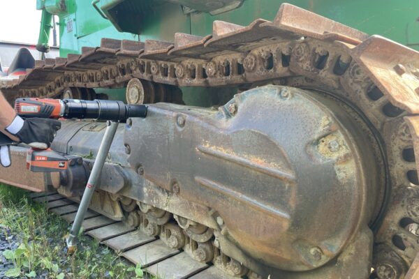A person is tightening a bolt on a bulldozer using the Plarad DA2 Nutrunner/torque wrench.
