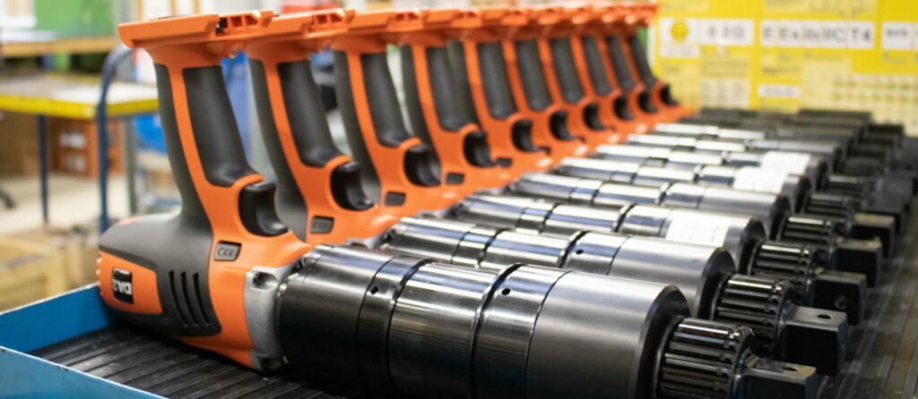 IMG_9679_1 A row of orange and black battery torque wrenches, neatly arranged on a shelf. Perfect for those looking to rent from Plarad.