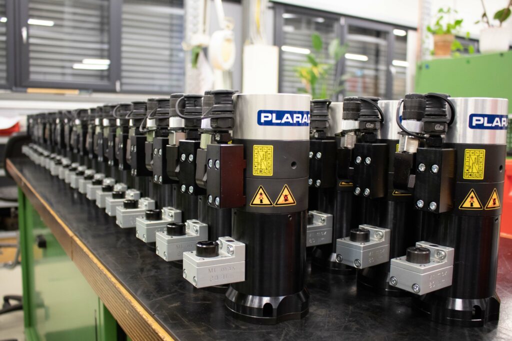 A row of identical hydraulic tensioners ready for export. It is displayed in workshop background.