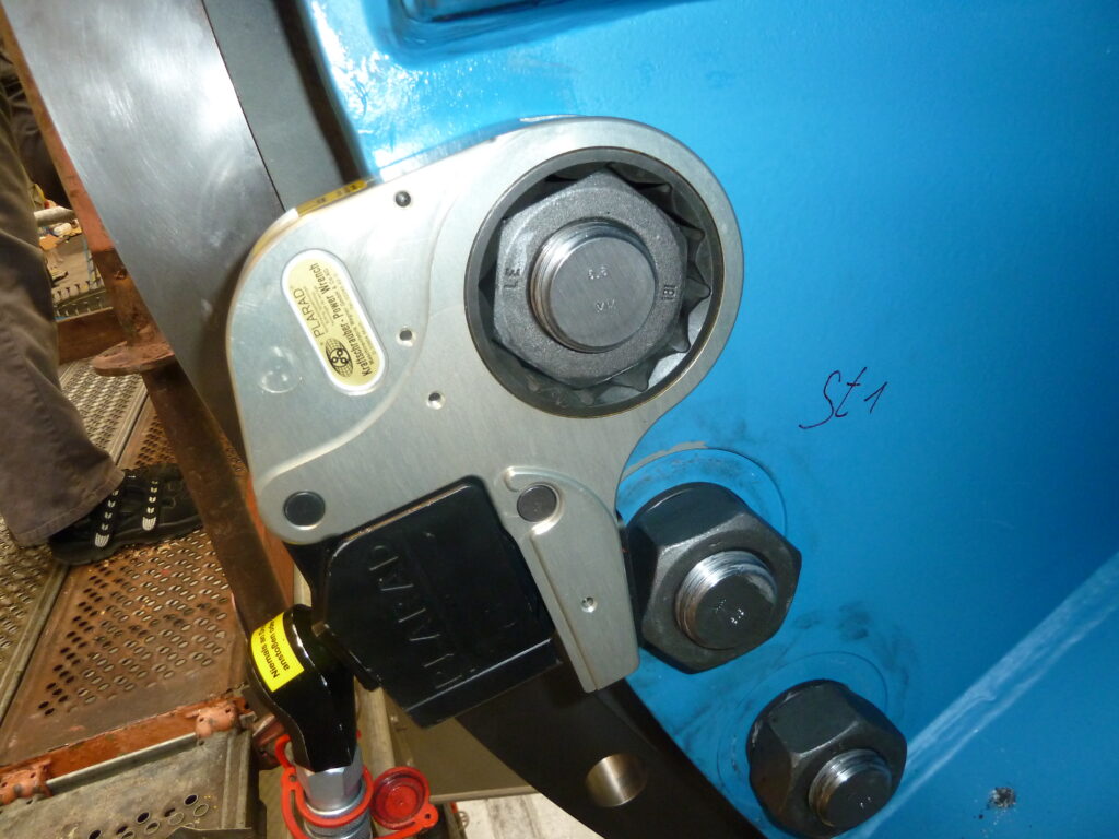 Demo Bilder Fürstenberg (66) Close-up of a Plarad FSX hydraulic flange torque wrench, securely fastened with bolts to a large blue metal surface.