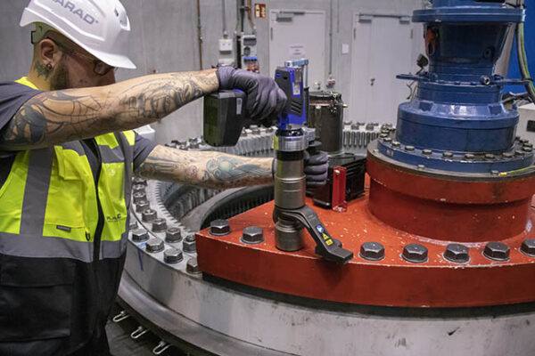 A person uses a power tool to tighten bolts on industrial equipment, demonstrating the precision and reliability of the "Made in Germany" DA2 Safety battery nutrunner.