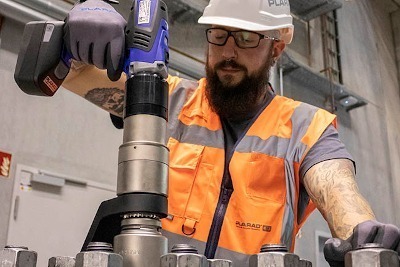 Drehmomentschrauber_anwendung_plarad A worker in protective gear expertly operates machines, using the precision of PLARAD's cordless DA2 power torque wrench and bolting technology in an industrial environment.