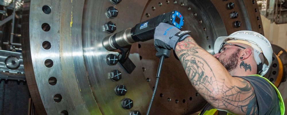 A worker in protective clothing expertly applies a 'Made in Germany' torque wrench to a large metal bolt, demonstrating the precision of high-quality bolting technology.