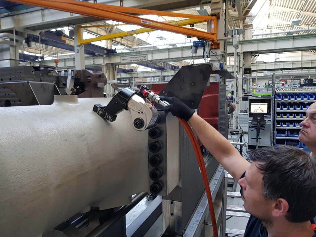 20190416_111356 Two men expertly operate industrial machinery in a factory, surrounded by the powerful hydraulic square drive wrench from Plarad and other large equipment in the background