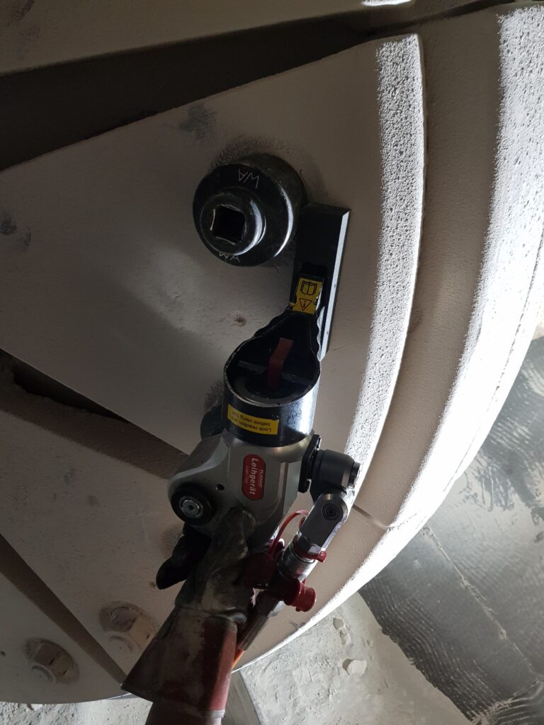 20190425_095521 A hydraulic square drive wrench from Plarad is a mechanical tool that is carefully attached to bolts and various components on a large metal surface, ensuring reliability and precision.