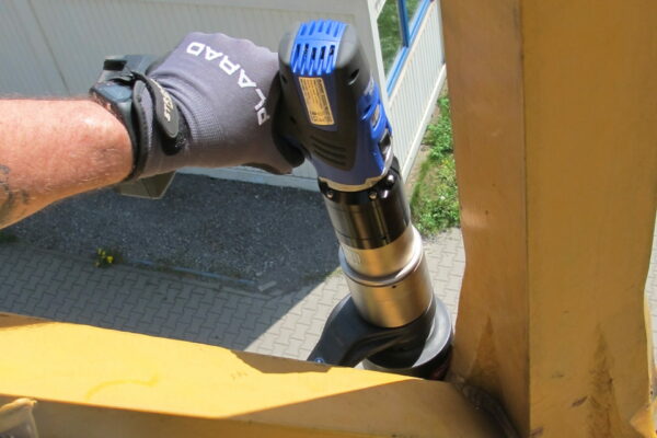 A worker expertly uses the battery-powered torque wrench and bolting technology from PLARAD 🔧 on a metal structure outdoors, ensuring precision and efficiency with every turn