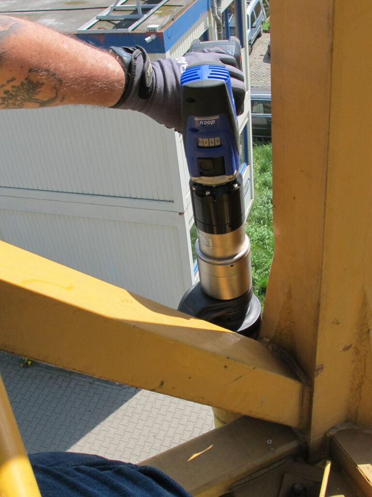 IMG_1964 A worker expertly uses the battery-powered torque wrench and bolting technology from PLARAD 🔧 on a metal structure outdoors, ensuring precision and efficiency with every turn.