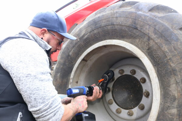 IMG_3940 A man uses the DA2 battery-powered torque wrench and bolting technology from PLARAD during the maintenance of a large tractor/forester/bus tire, ensuring precision and efficiency.
