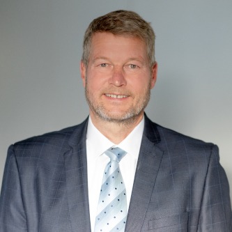 Matthias Scheuerlein, Technischer Vertrieb und verantwortlich für die Regionen Mecklenburg-Vorpommern und Brandenburg in Deutschland, trägt einen Anzug mit Mantel und steht für Fragen zur Verfügung.