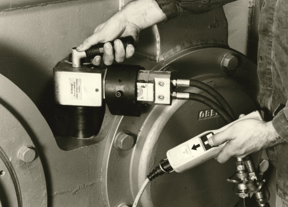 A person expertly uses the Evolution hydraulischer Drehmomentschrauber von Plarad on industrial machinery, showcasing innovation in heavy industry.